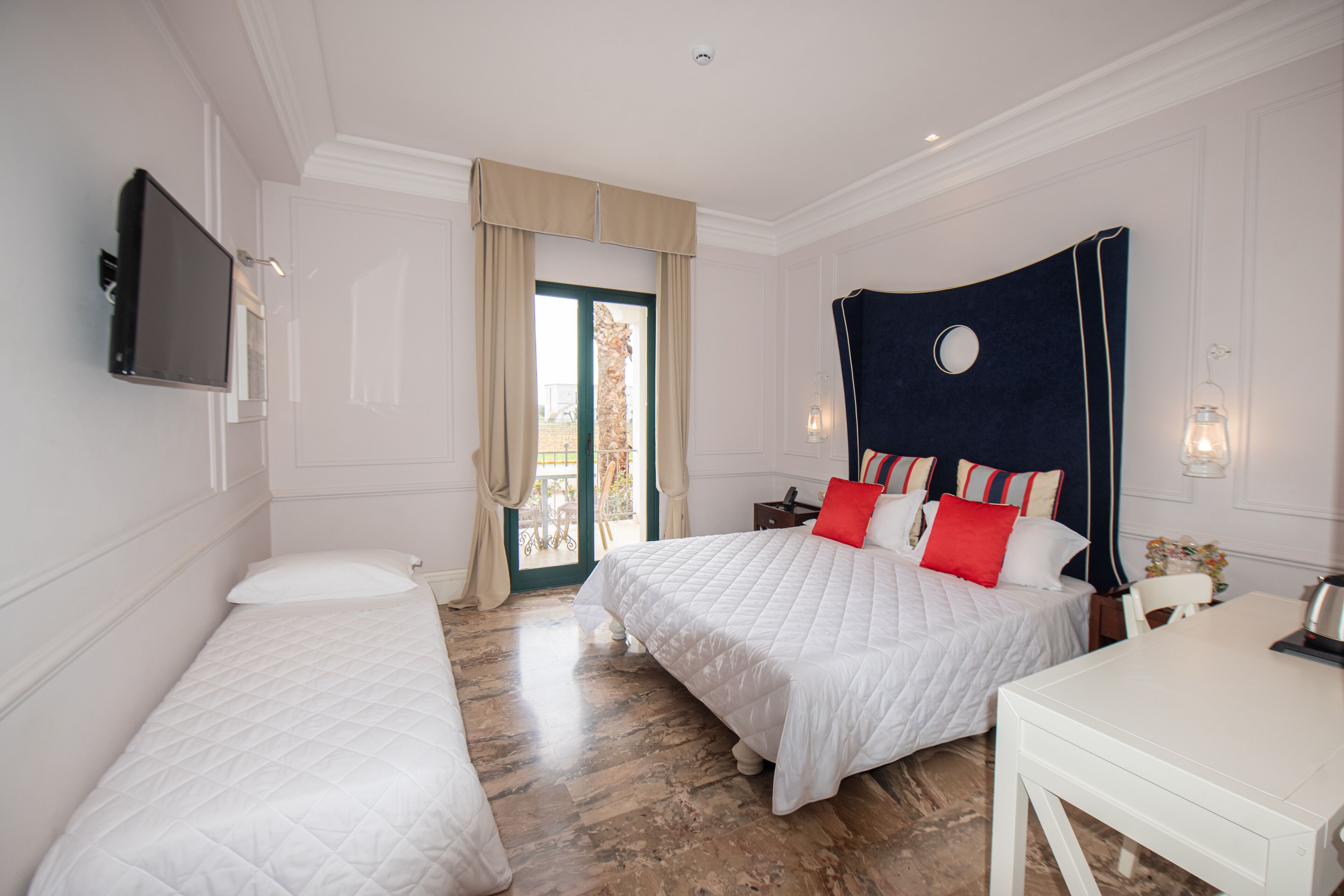 Habitación de hotel con dos camas, televisión, escritorio y vistas al exterior.