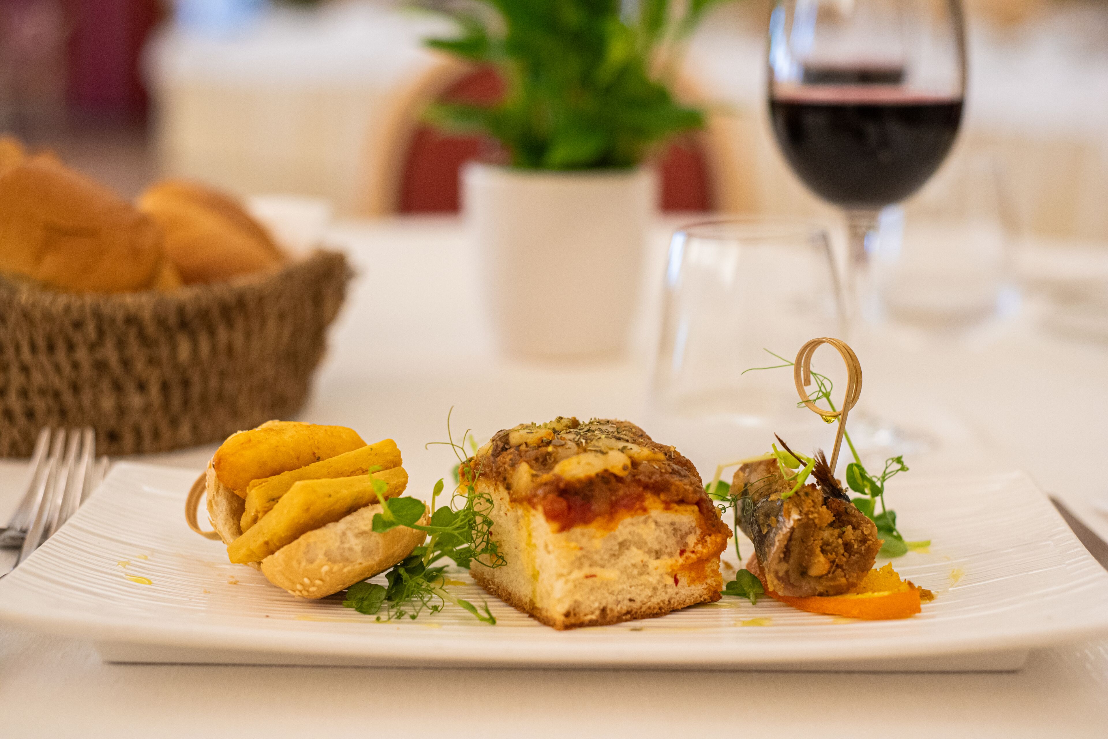 Un plato de comida con carne, verduras y un recipiente pequeño de comida amarilla, posiblemente un acompañamiento.