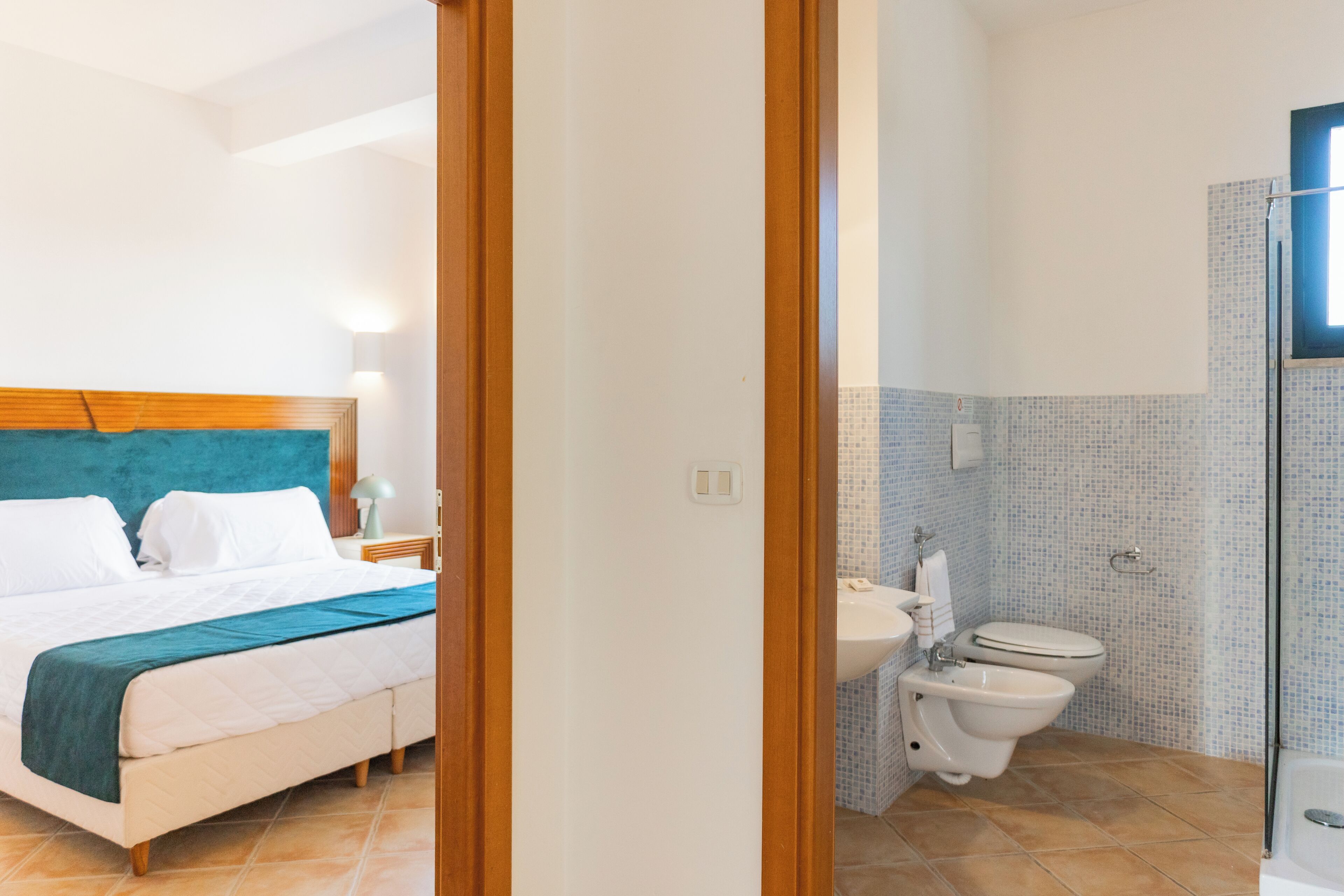 A hotel room with a bed, a bathroom with a toilet and sink, and a shower area.