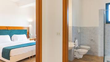 A hotel room with a bed, a bathroom with a toilet and sink, and a shower area.
