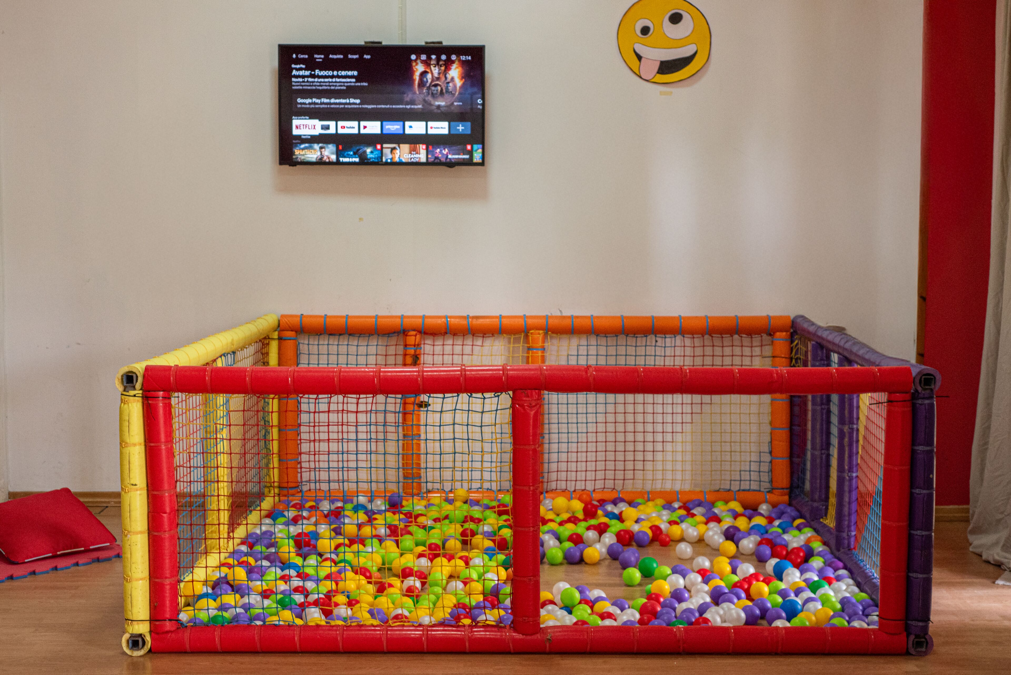 Een speelbox met kleurrijke ballen en een televisiescherm waarop een film draait.