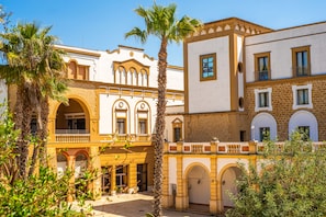A courtyard with a building featuring arches and a balcony. - Baglio Basile Hotel (Petrosino)
