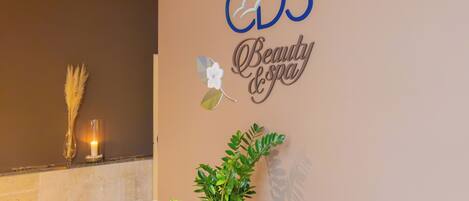 A wall with a sign that reads 'CDS Beauty Spa' and a potted plant on a counter.