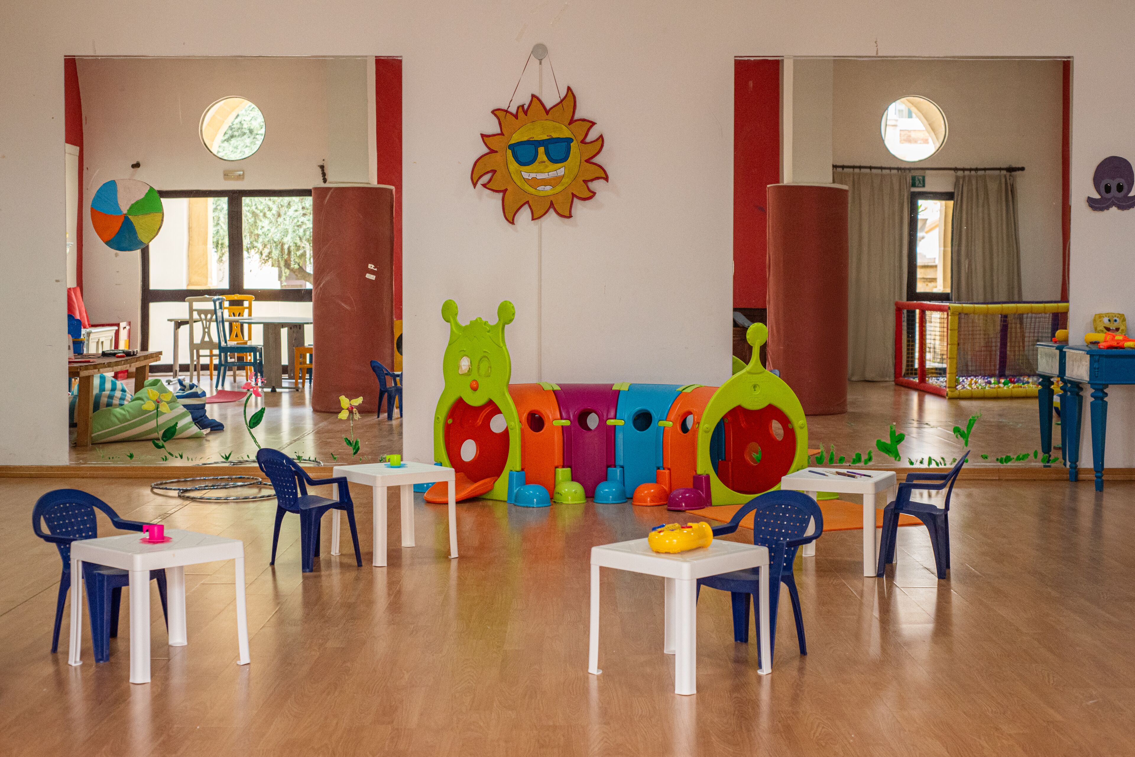 Una sala giochi per bambini con strutture colorate, tavoli e sedie.
