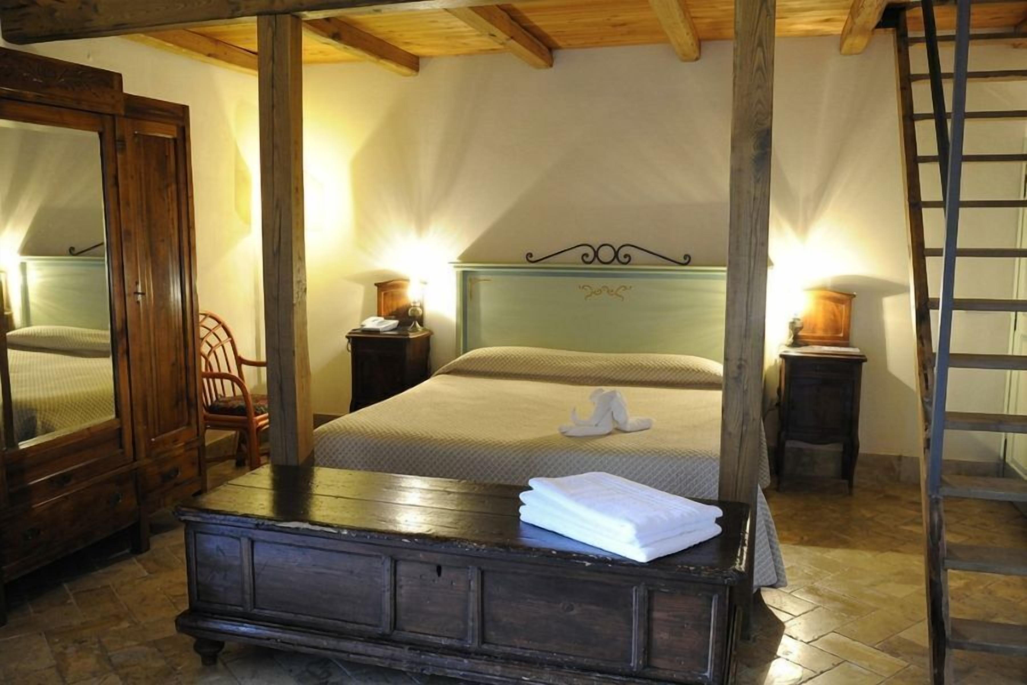Ein Schlafzimmer mit einem hölzernen Bett, einem Nachttisch, einem Stuhl, einer Kommode und einer Leiter.