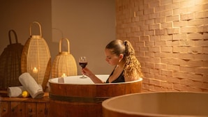 A spa setting with a wooden bathtub, candles, and a glass of wine. - Baglio Basile Hotel (Petrosino)