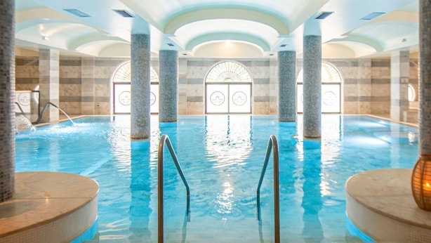 An indoor swimming pool with clear water, surrounded by stone walls and columns, and a tiled floor. - Baglio Basile Hotel (Petrosino)