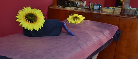Een kamer met een bed, een houten kast, een radio en twee zonnebloemen op het bed.