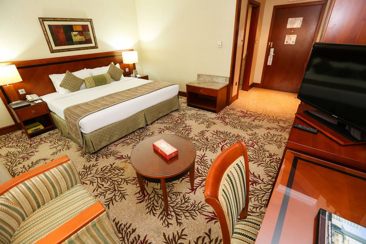 Una habitación de hotel con una cama, televisión, una mesita y una silla.