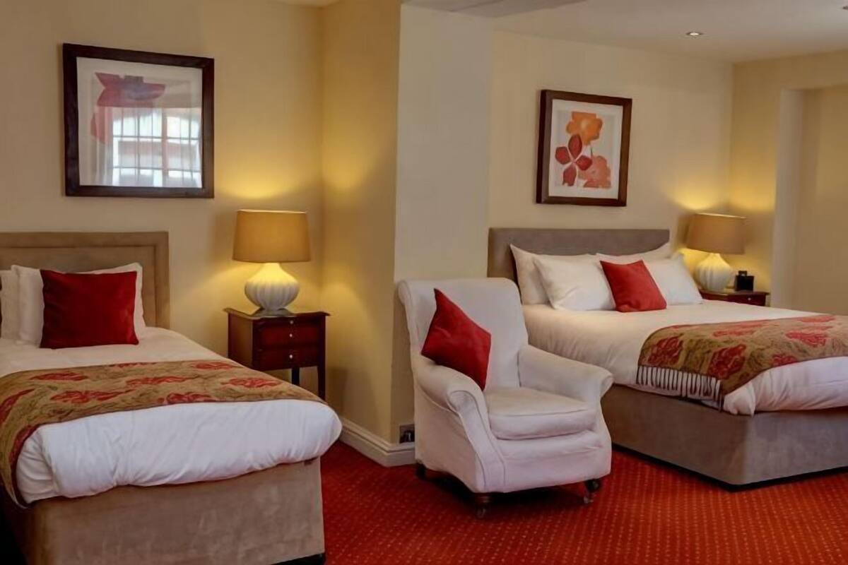 Een hotelkamer met twee bedden, een stoel en twee nachtkastjes met lampen.