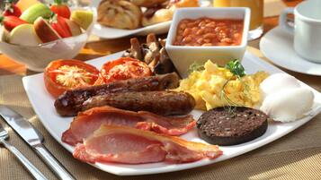 A breakfast plate with sausages, bacon, eggs, and beans.