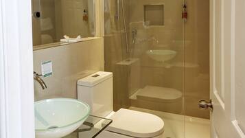 Une salle de bain moderne avec une douche à parois de verre, un lavabo en verre et des toilettes blanches.