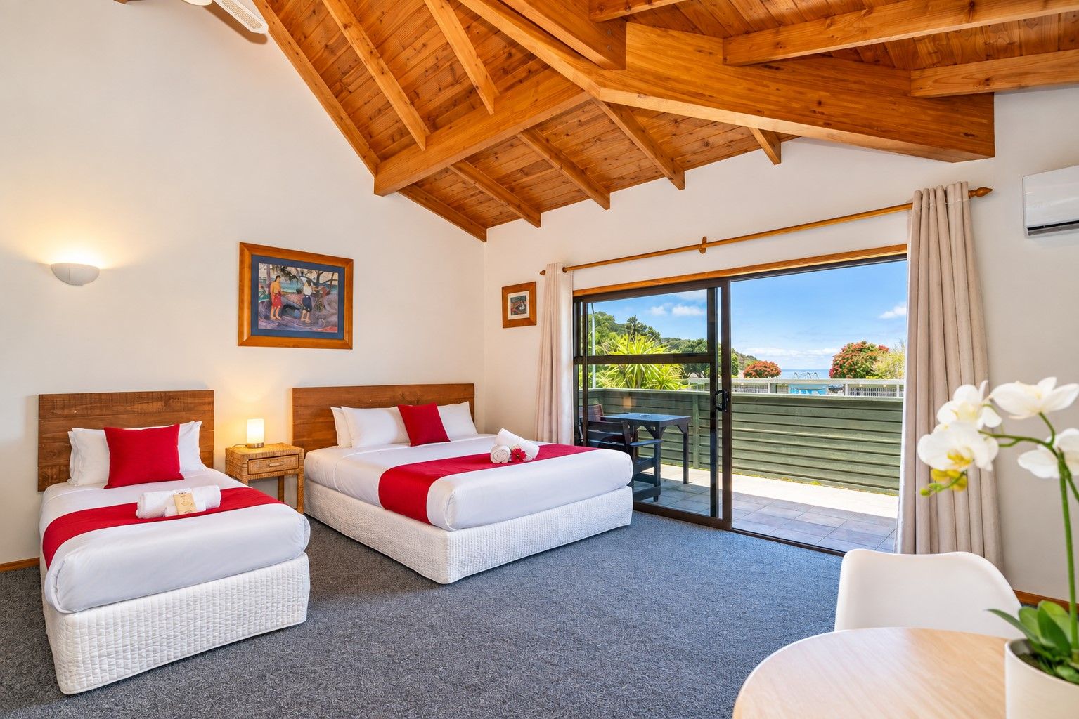 A hotel room with two beds, a balcony, and a view of the sea.