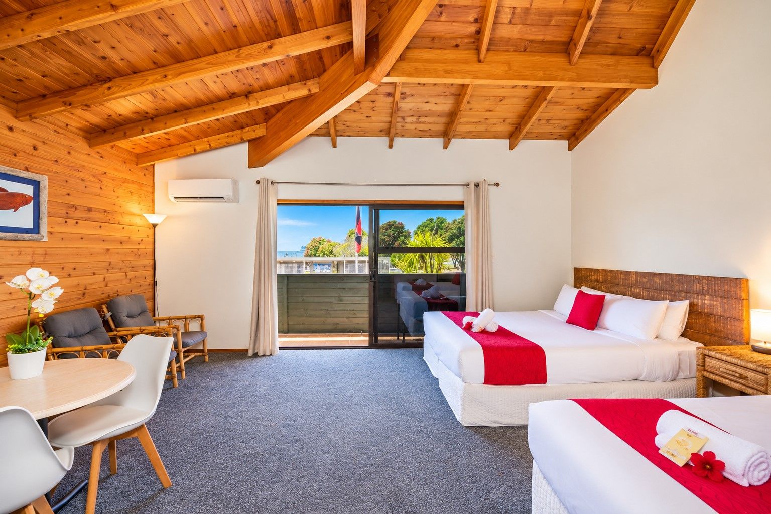 Habitación de hotel con balcón, dos camas, zona de comedor y vistas al exterior.