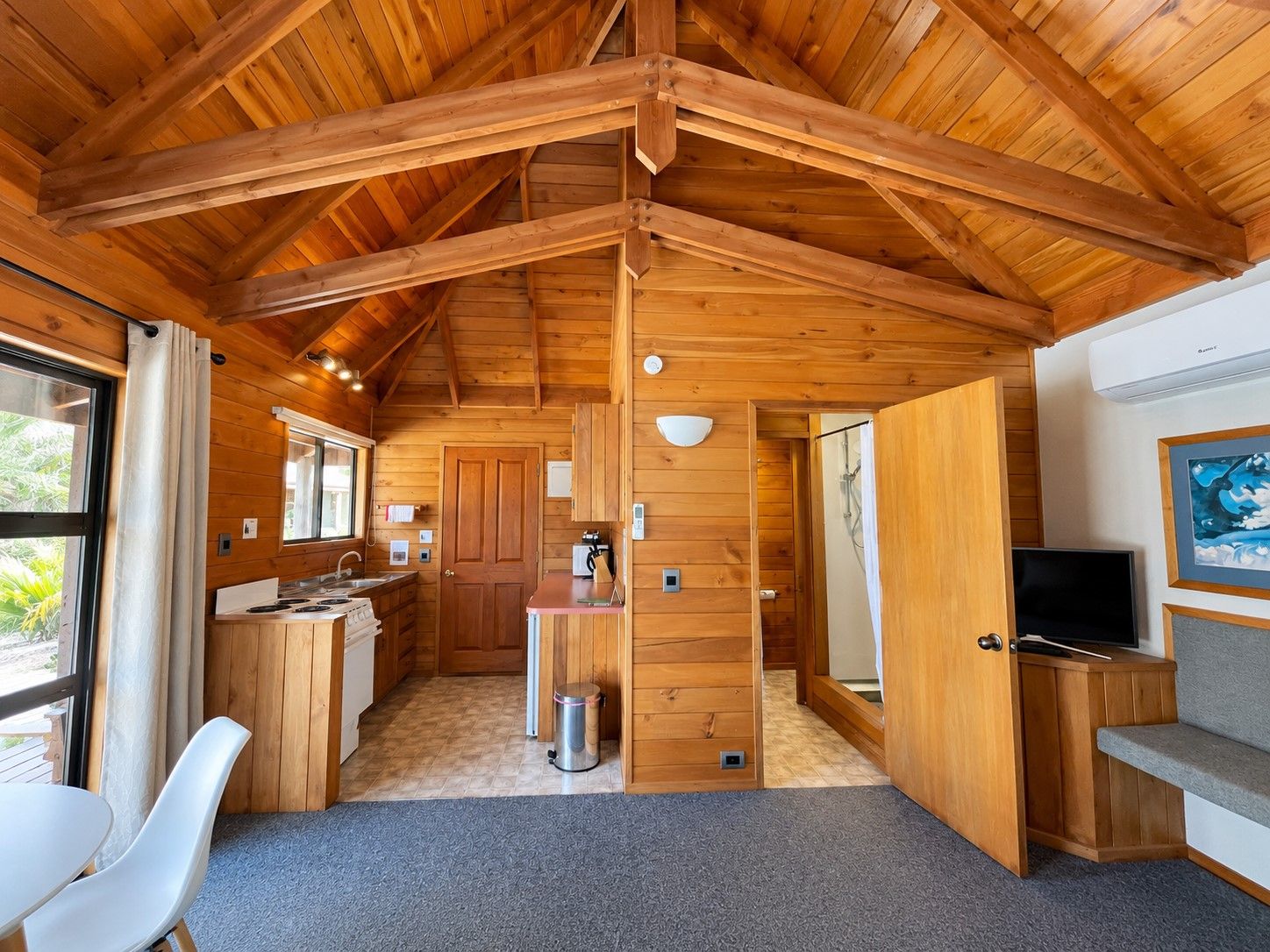 Una cabaña compacta con cocina, comedor y zona de estar con televisor.