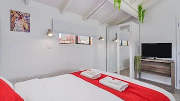 Habitación de hotel con cama, televisión, ventana y espejo.