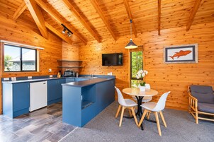 Una cocina moderna con armarios azules, una isla central y un comedor con sillas blancas.