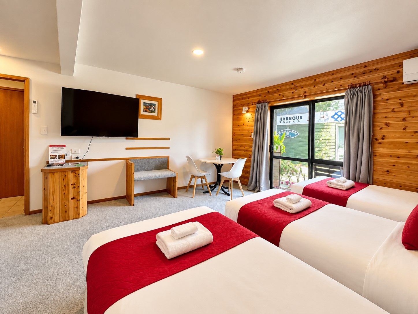 A hotel room with two beds, a desk, a chair, a television, and a window with curtains.