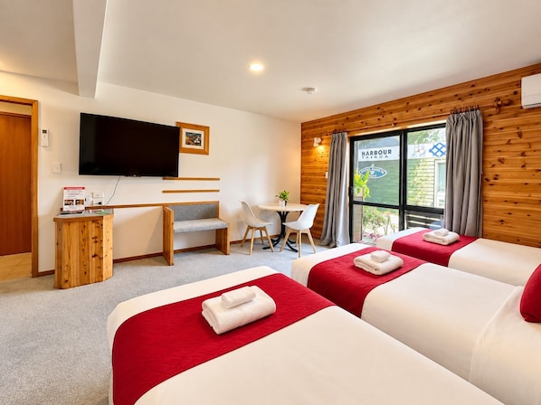 A hotel room with two beds, a desk, a chair, a television, and a window with curtains.