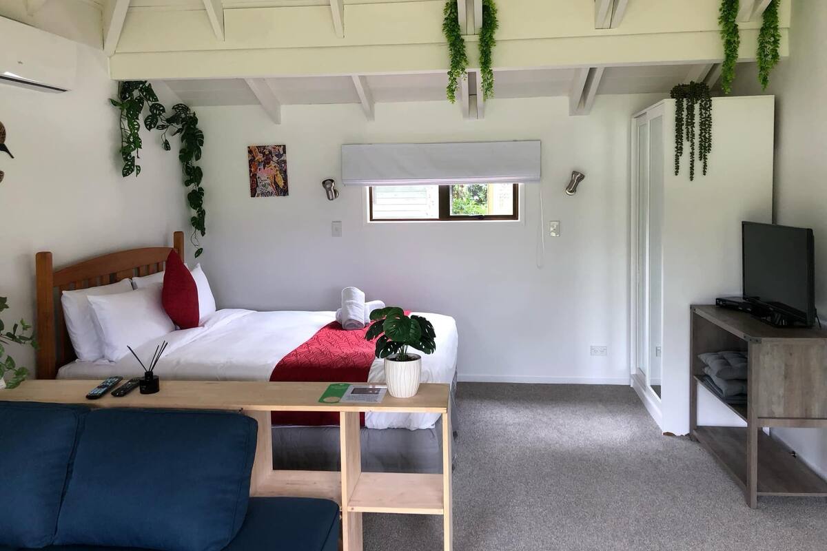 Ein gemütliches Zimmer mit Bett, Fernseher, Schreibtisch und Fenster.