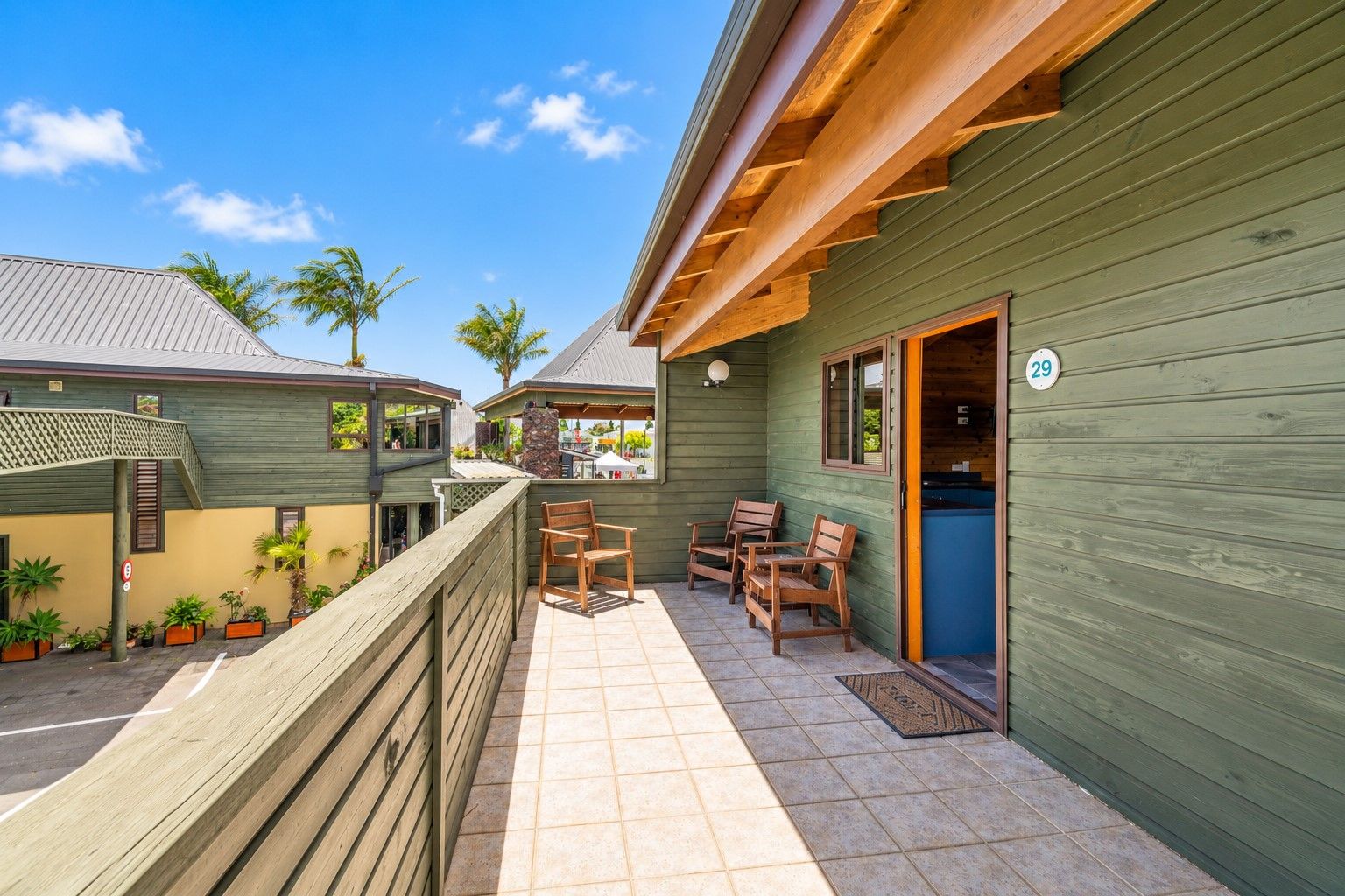 A wooden building with a covered patio area, outdoor seating, and a visible door number.