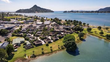 Vista aérea de una zona residencial costera con casas, un pequeño lago y una colina distante.