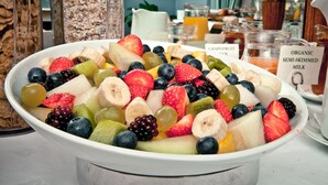 Eine Schüssel mit einer Auswahl an Früchten, darunter Erdbeeren, Bananen, Trauben und Blaubeeren.