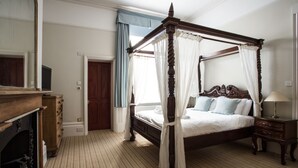 Ein Bett mit Himmelbett, ein Holzkapiton, ein Nachttisch und ein Kamin.