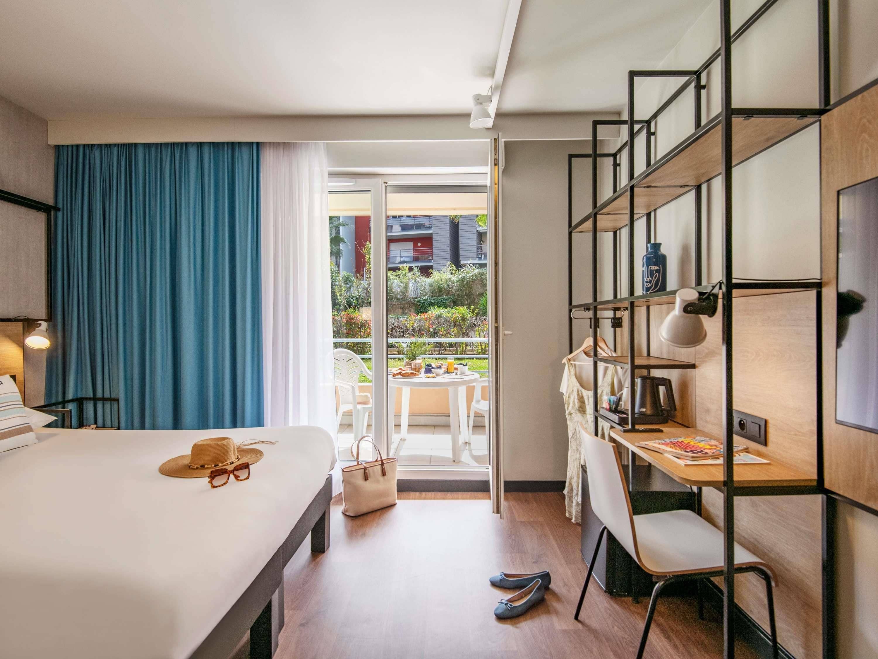 Een hotelkamer met een bed, een bureau en een balkon.