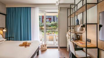 Een hotelkamer met een bed, een bureau en een balkon.