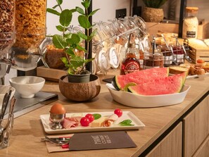 A breakfast buffet with various food items, a plant, and condiments. - Ibis Roquebrune Cap Martin Menton (Roquebrune-Cap-Martin)