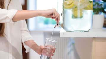 Una persona sirve agua de un recipiente grande en un vaso.