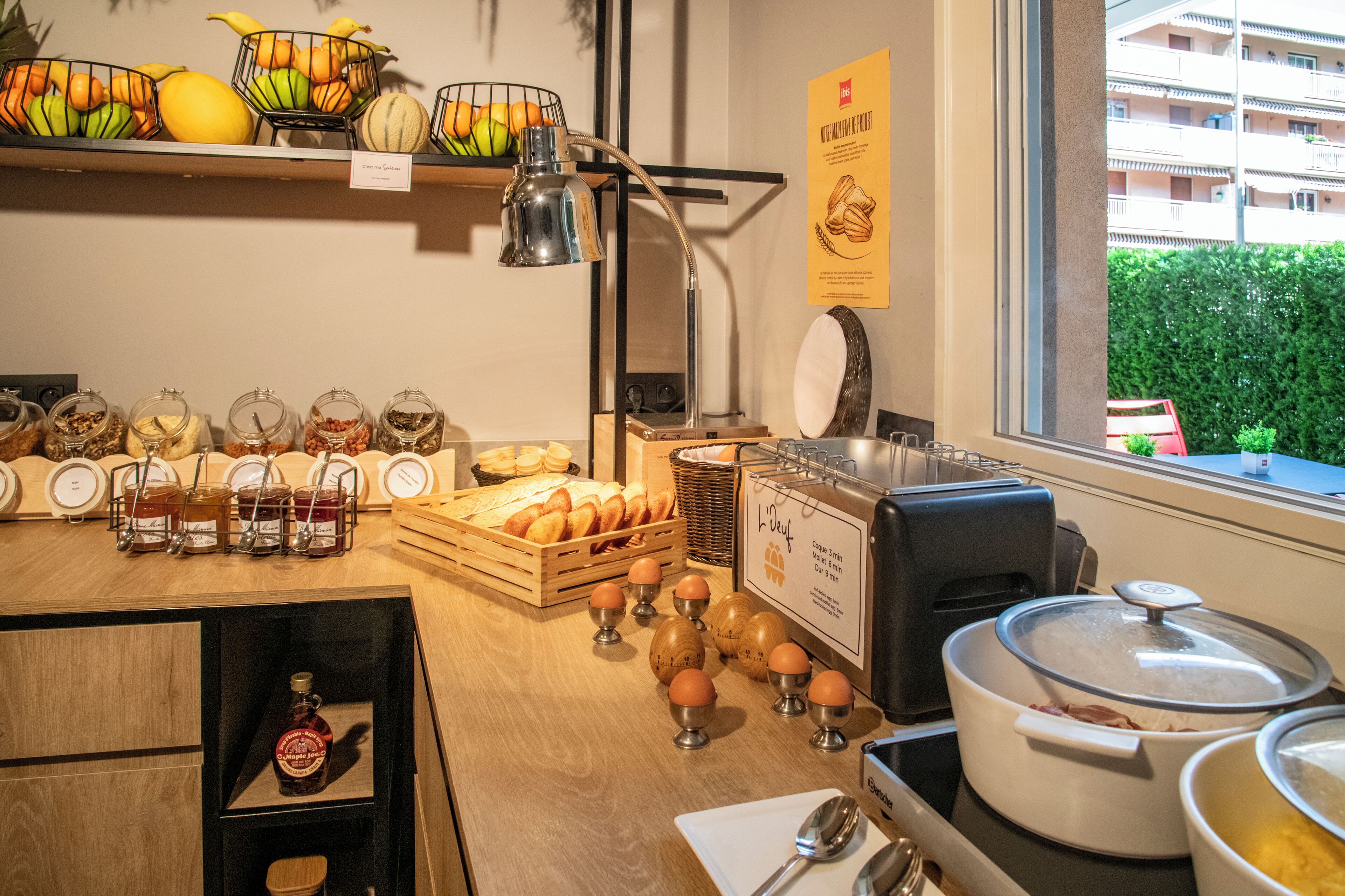 Een ontbijtbuffet met diverse gerechten, een koffieapparaat en uitzicht op het omliggende landschap.