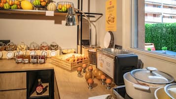A breakfast buffet with various food items, a coffee machine, and a view of the outside.