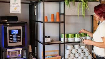 A coffee machine, shelves with mugs, and a sign about eco-responsibility.