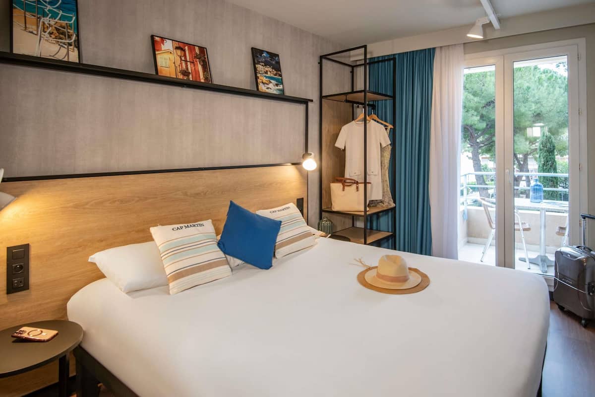 Une chambre d’hôtel avec un grand lit, une table de chevet, une armoire et une vue sur l’extérieur.