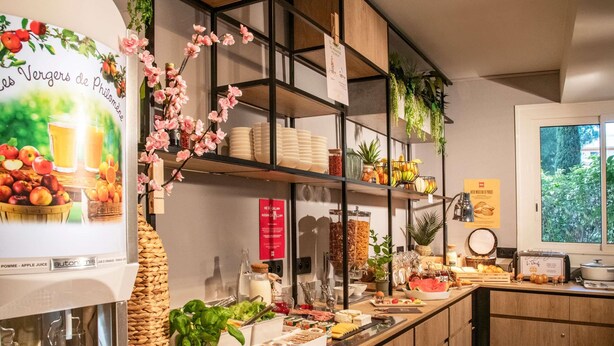 Ein reichhaltiges Frühstücksbuffet mit verschiedenen Speisen, einem Saftspender und Zierpflanzen.