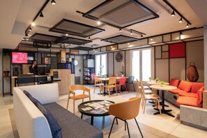 A modern interior with a seating area, a dining table, and a kitchen area. - Ibis Roquebrune Cap Martin Menton (Roquebrune-Cap-Martin)
