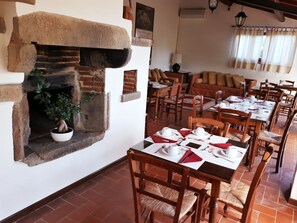 Un restaurante con paredes de ladrillo, chimenea, mesas y sillas de madera.