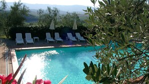 A pool with clear blue water, surrounded by white lounge chairs and umbrellas, with a view of distant mountains. - Agriturismo Antico Borgo Poggitazzi (Terranuova Bracciolini)