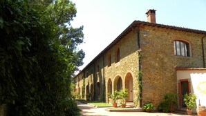 A stone building with arched windows and a courtyard. - Agriturismo Antico Borgo Poggitazzi (Terranuova Bracciolini)