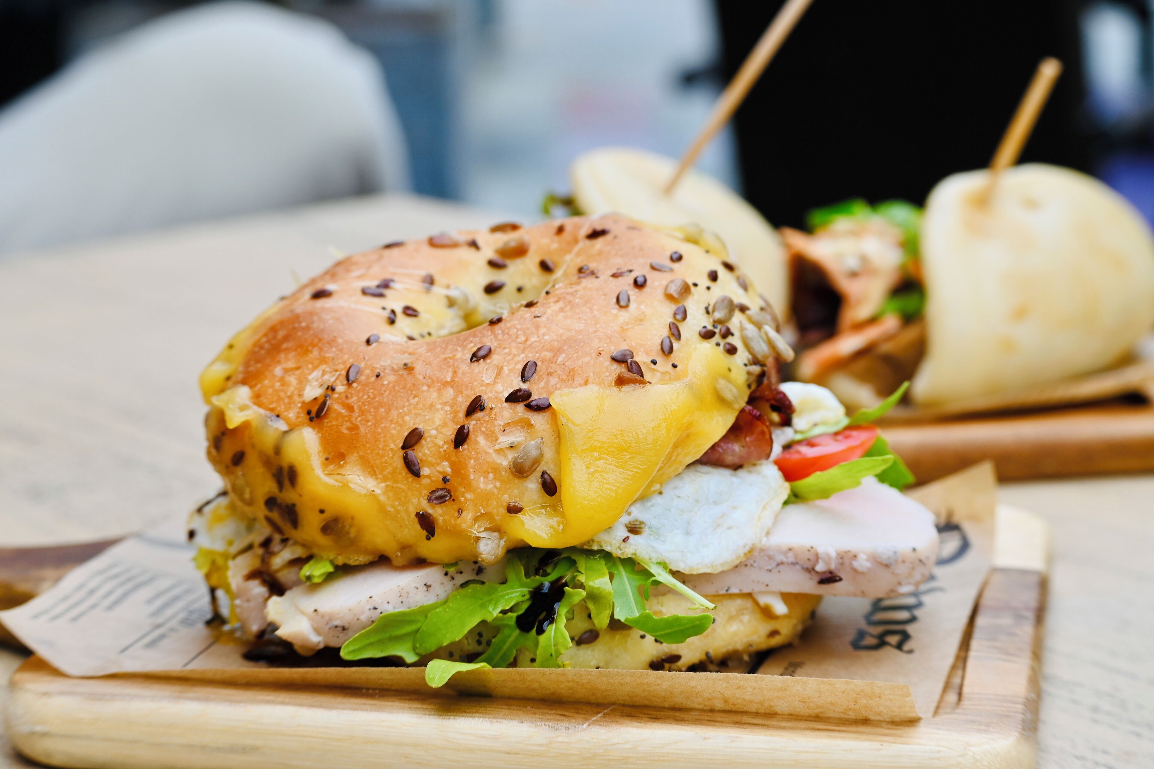 A sandwich with various ingredients and a wooden cutting board.