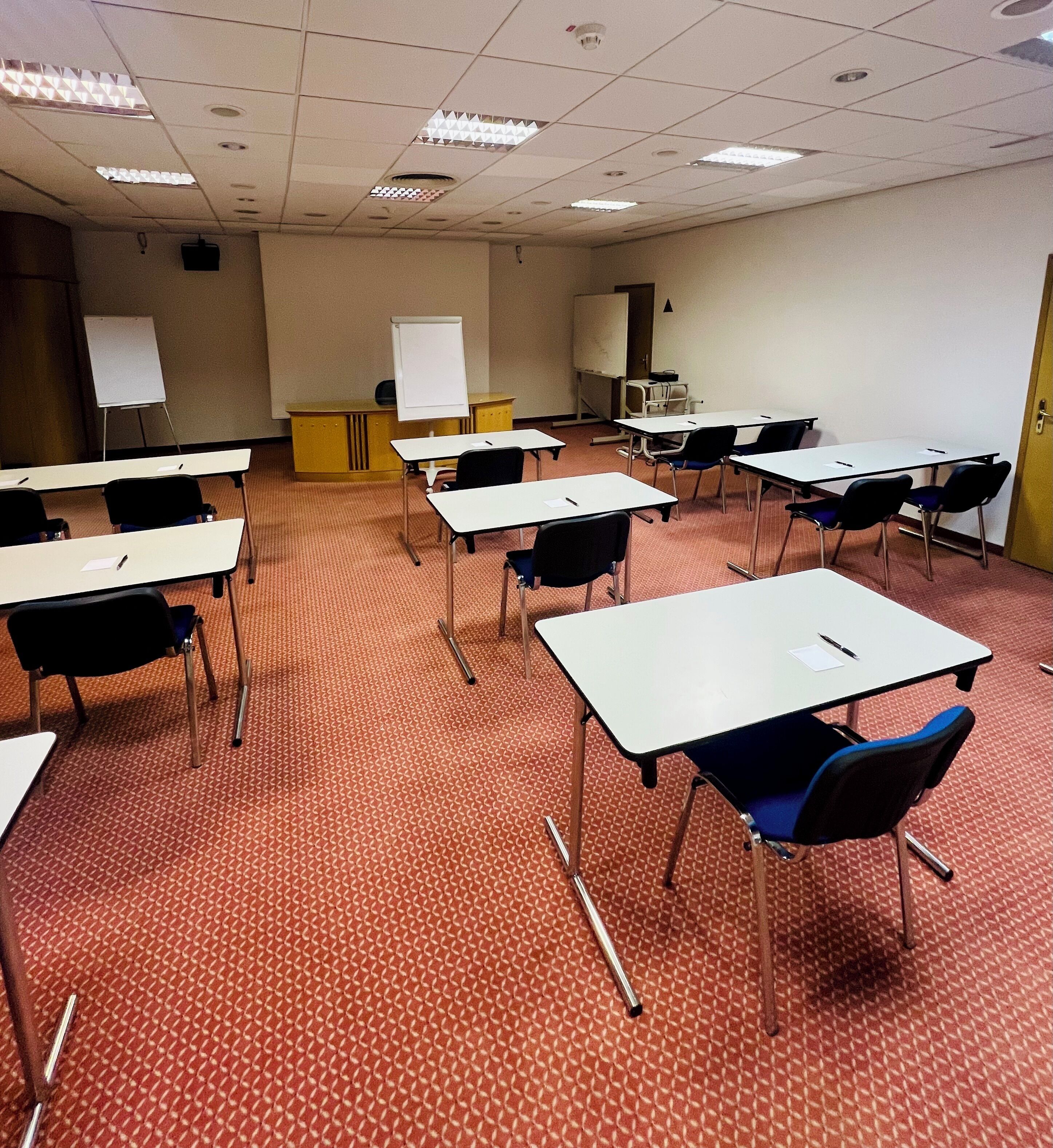 A classroom with desks, chairs, a whiteboard, and a projector screen.