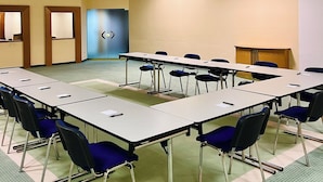 Ein Konferenzraum mit einem langen Tisch, blauen Stühlen und einer blauen Tür.