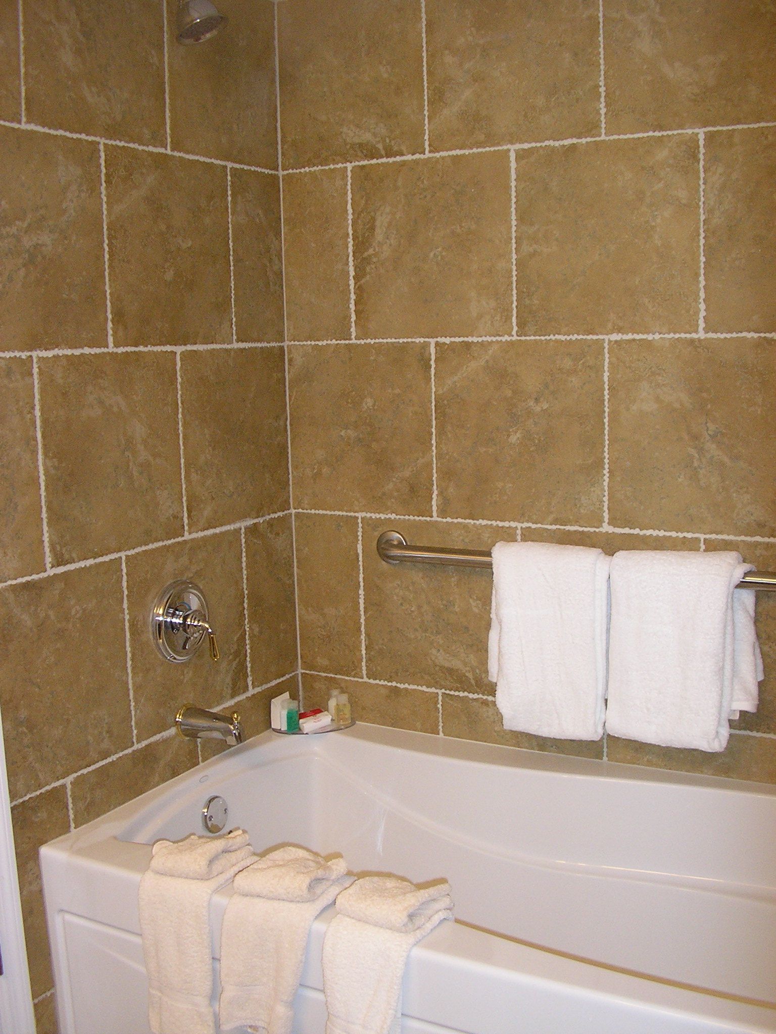 Une salle de bain avec une baignoire, un porte-serviettes et une pomme de douche.