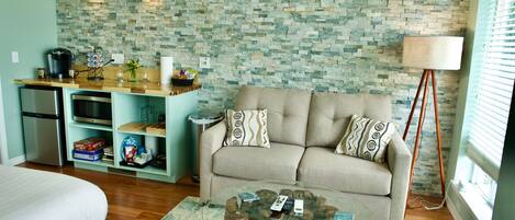 A compact living space with a kitchenette, a sofa, and a coffee table.