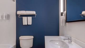 A bathroom with a white sink, a mirror, and a toilet against a blue wall.