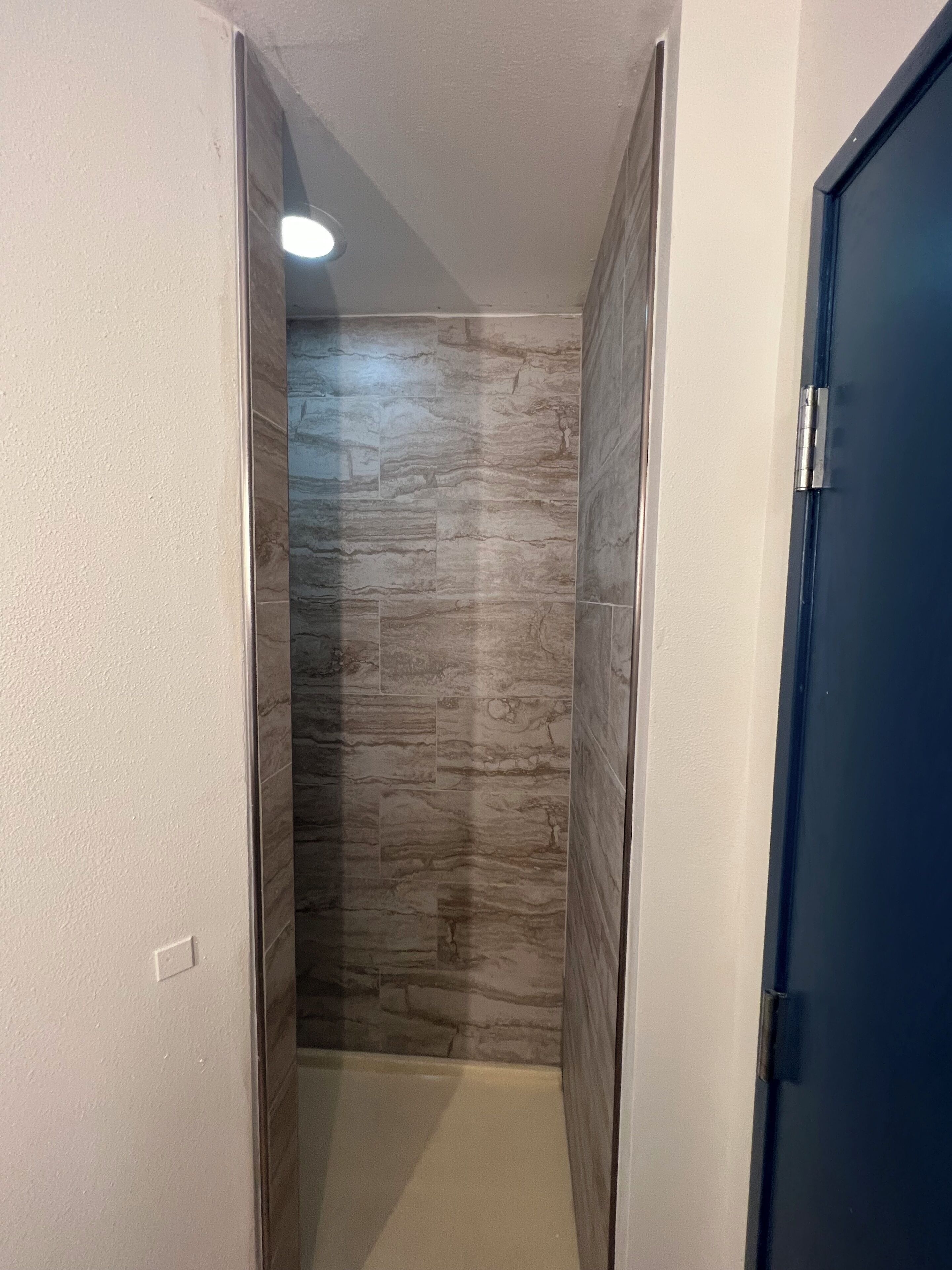 A narrow hallway with a tiled wall and a blue door.