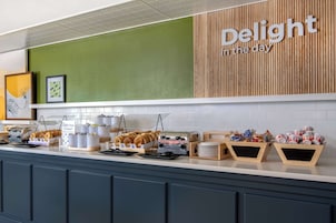 Montaje de desayuno buffet con diversos alimentos y un letrero que dice 'Delight in the day'.