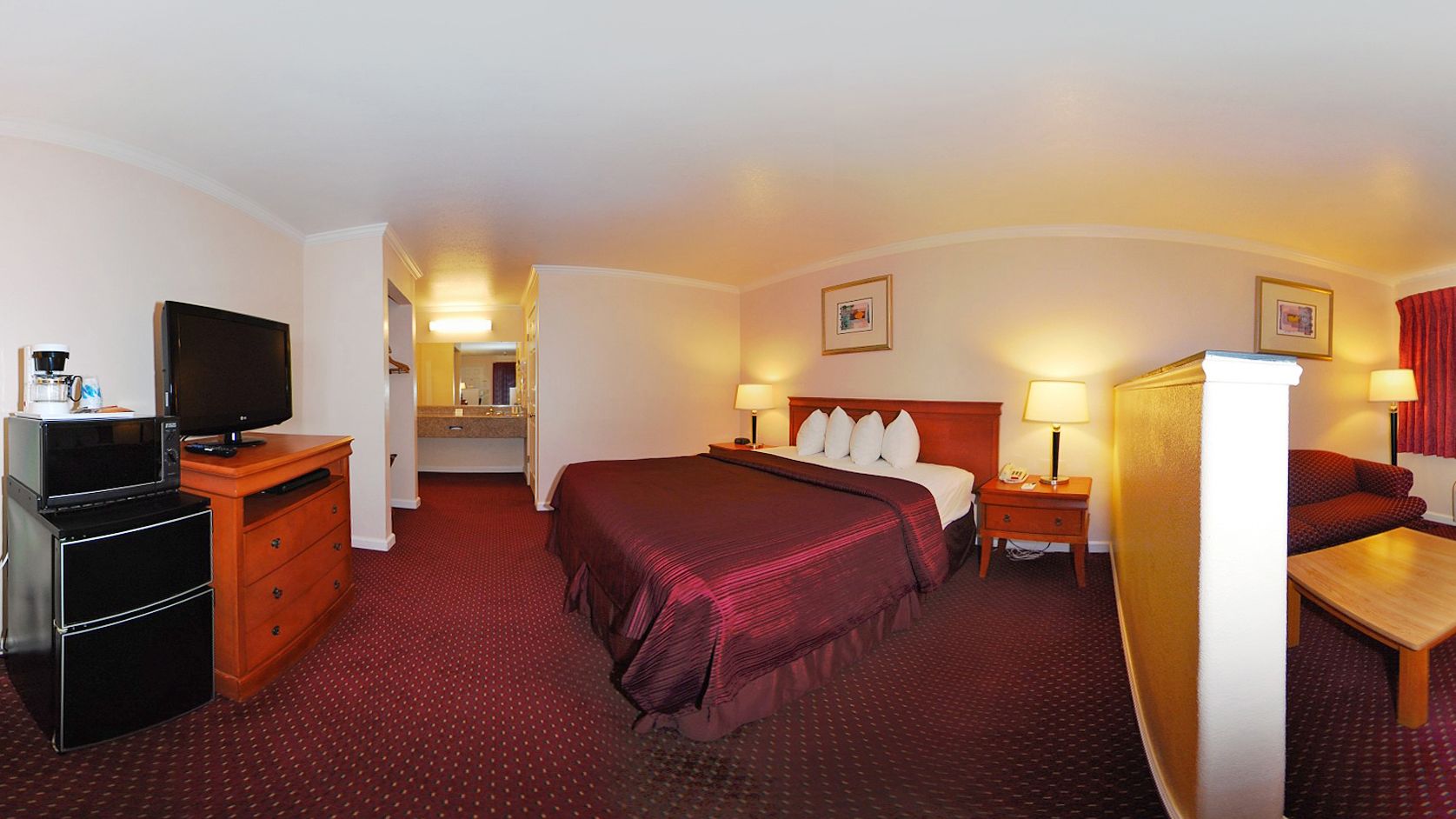 Une chambre d’hôtel avec un grand lit, une télévision, un bureau et une salle de bain visible à travers une porte ouverte.